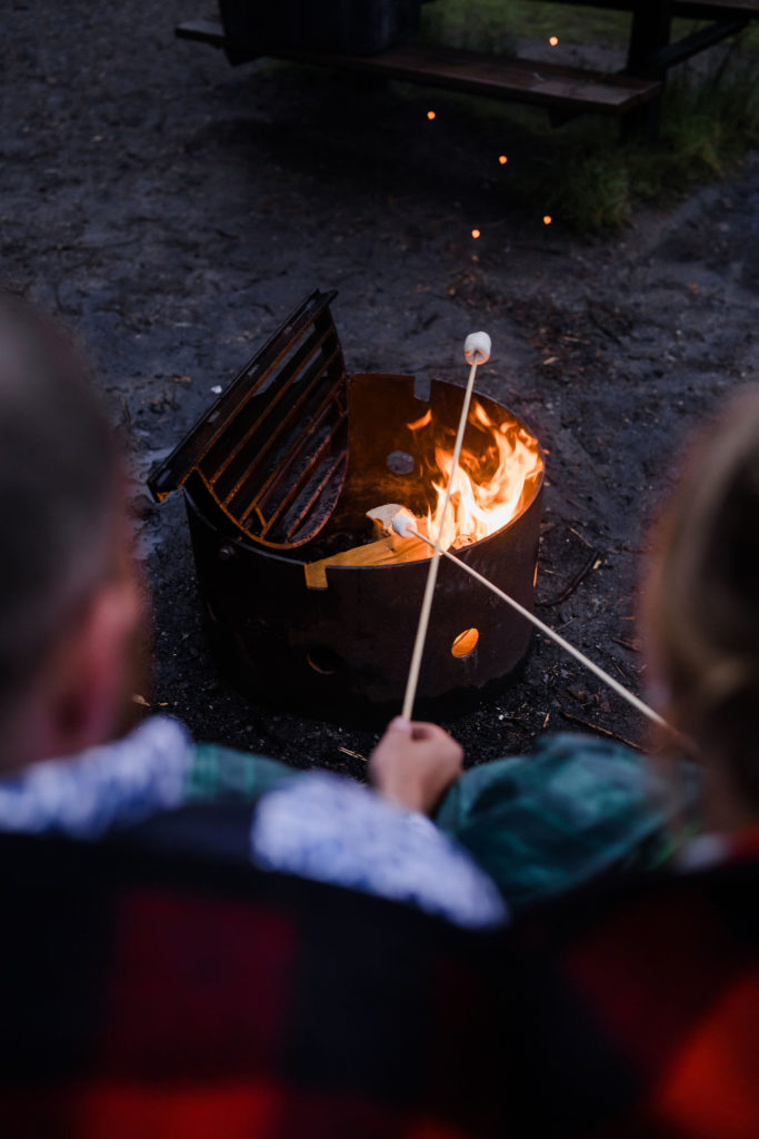 two marshmallows roasting on sticks above fire