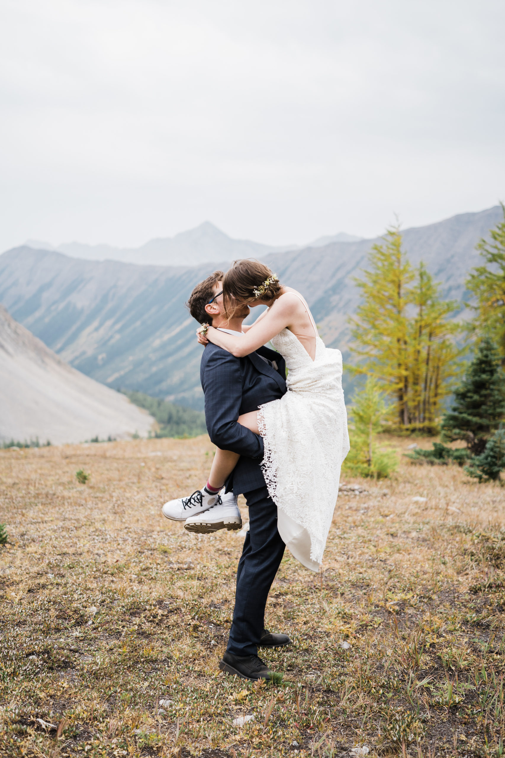 groom is holding bride up with her legs wrapped around him during a fall hiking elopement in alberta