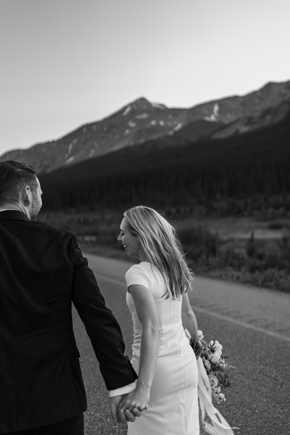 black and white photo of bride running down the road on the  Icefields Parkway in Banff National Park during sunrise elopement