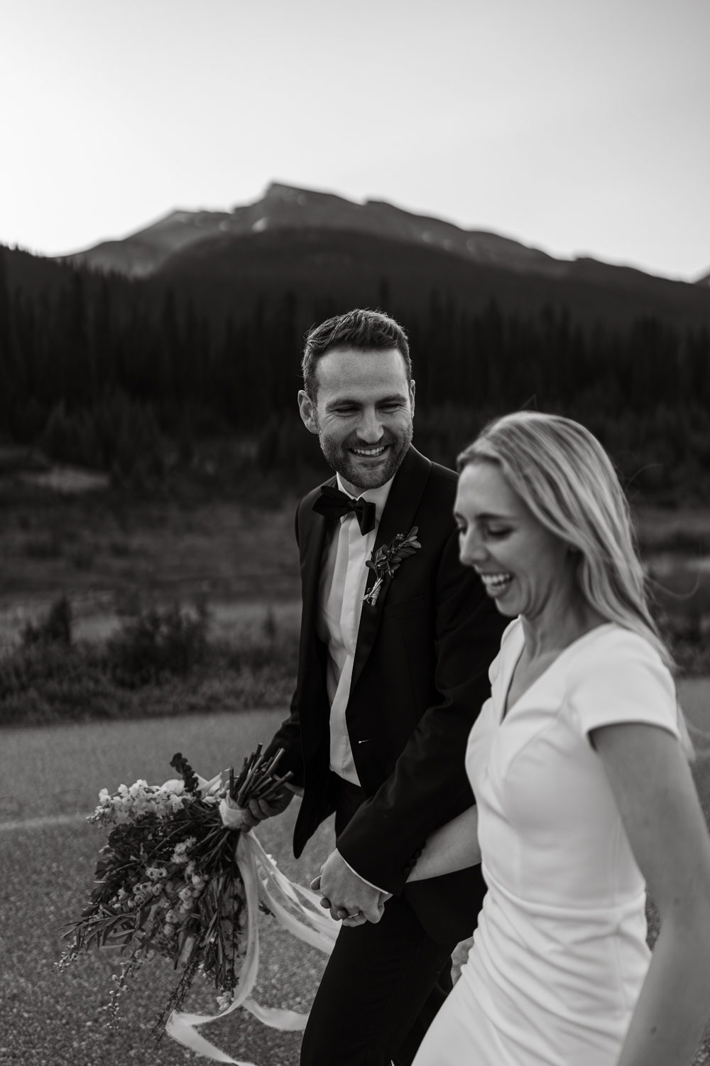black and white photo of groom smiling at bride while they run