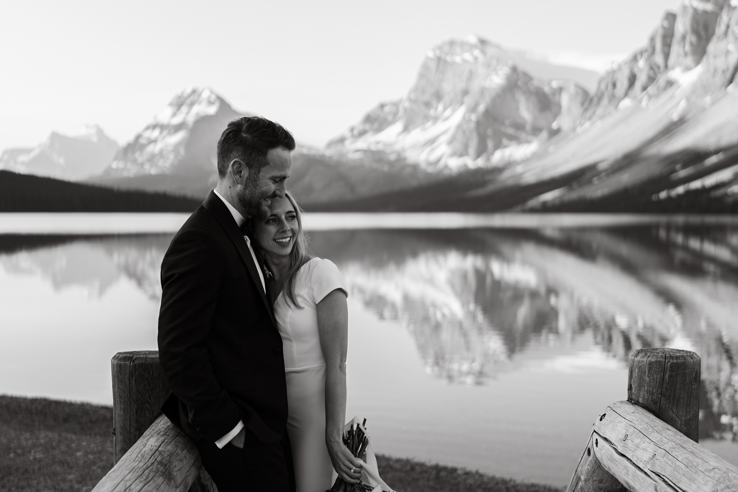 black and white photo of bride and groom on bridge at Bow Lake in Banff National Park at sunrise
