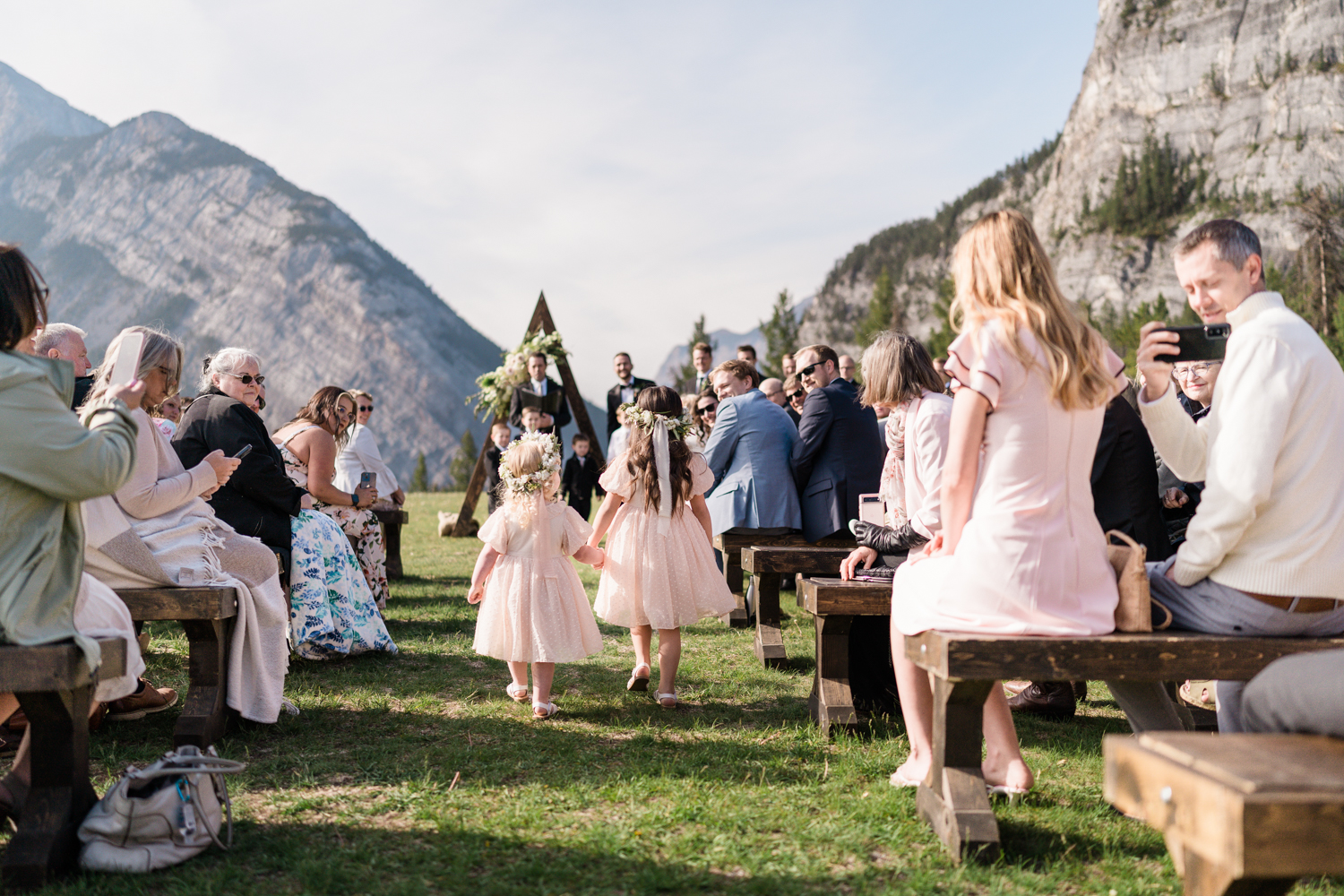 two flower girls dressed in pink walk down the aisle at Tunnel Mountain in Banff 