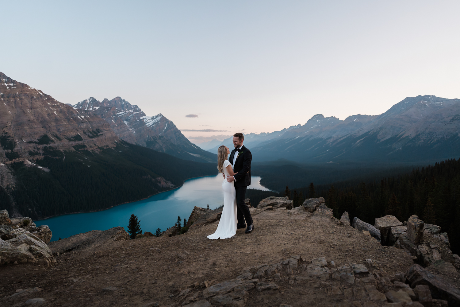 Bride and groom embrace at overlook by Peyto Lake before their sunrise elopement