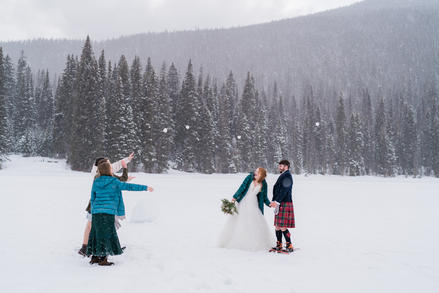 three friends snow snowballs at bride and groom during a winter emerald lake elopement