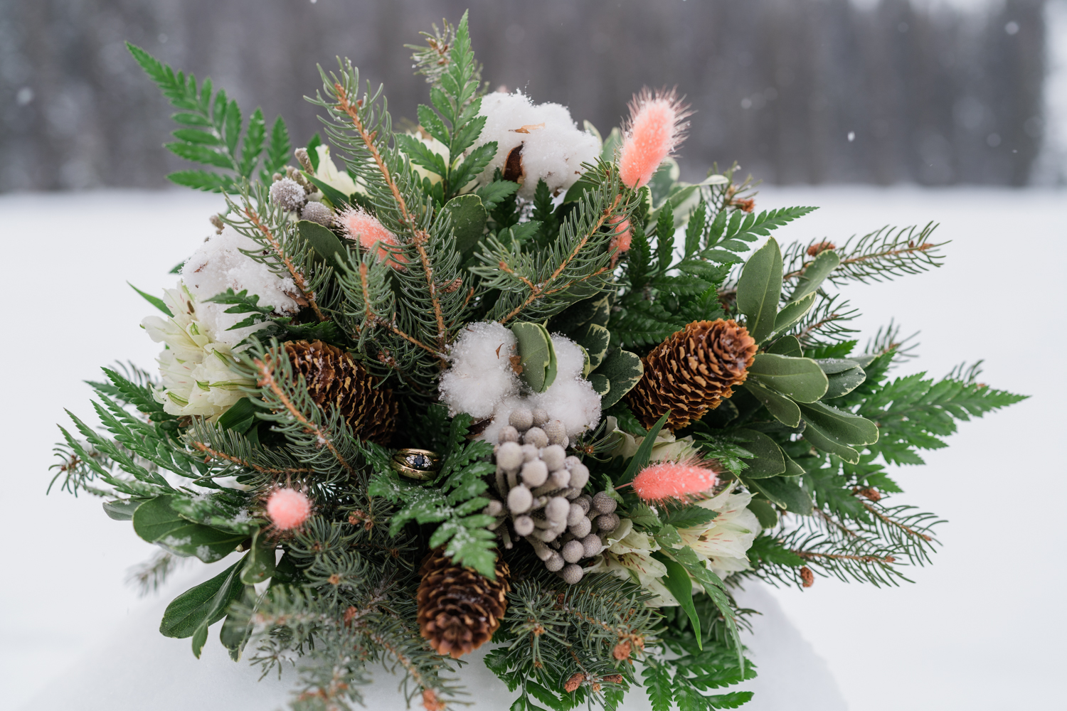 three rings nestled inside winter bouquet in the snow