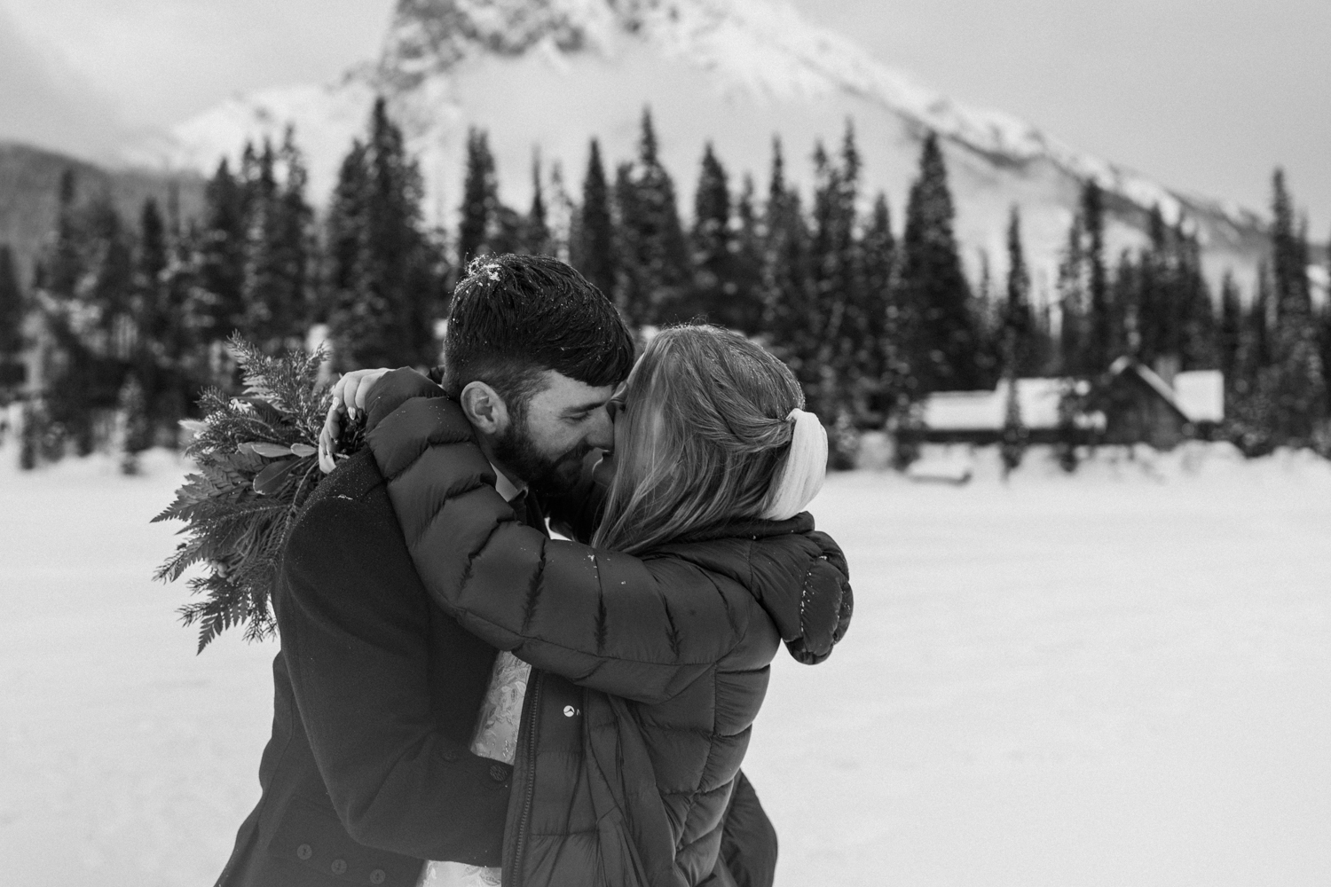 black and white photo of bride and groom smiling and kissing during their winter Emerald Lake elopement