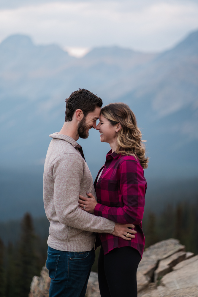 man and woman stand close touching foreheads and laughing during a Peyto Lake Engagement session