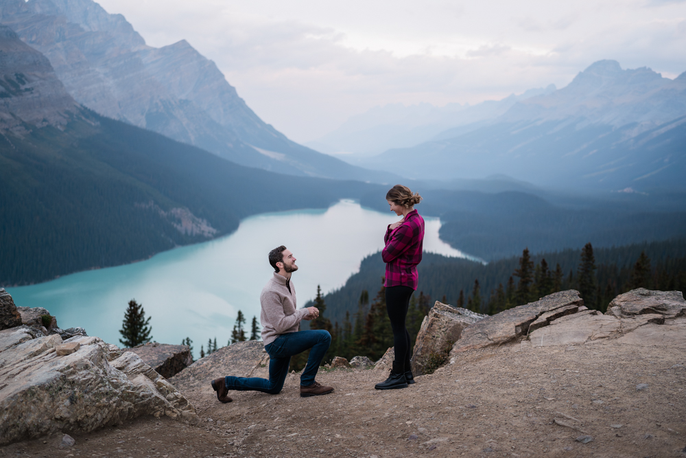 man proposes at Peyto Lake at sunrise to his girlfiend.