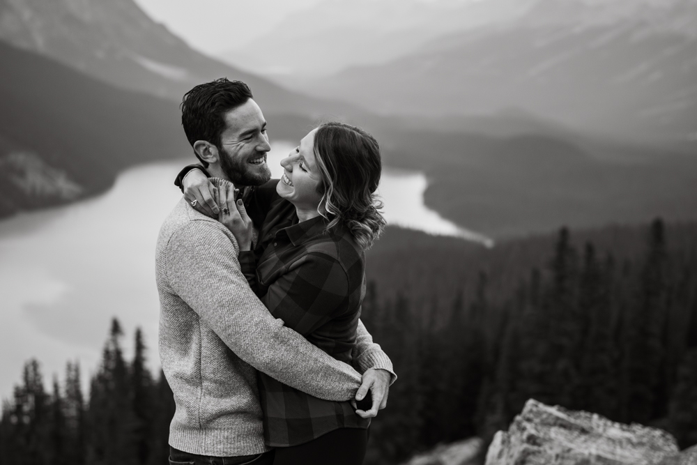 black and white photo of a man and woman embracing and laughing at her proposed at Peyto Lake in Banff National Park