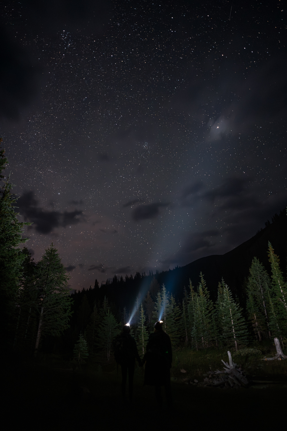 Couple points their headlamps up to the stars the morning of their Alberta camping elopement.