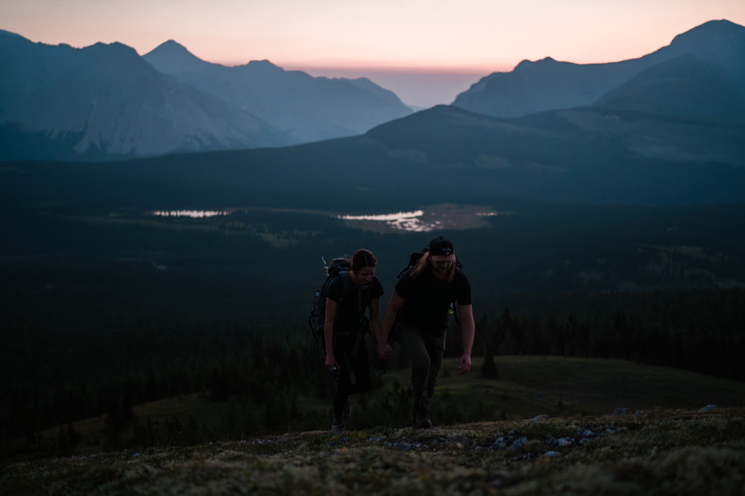 Couple hikes a mountain pre sunrise on their backcountry camping elopement.