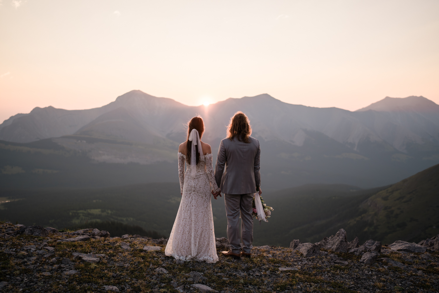 The rising sun casting a golden glow on the couple during their intimate backcountry camping elopement in Alberta's Kananaskis.