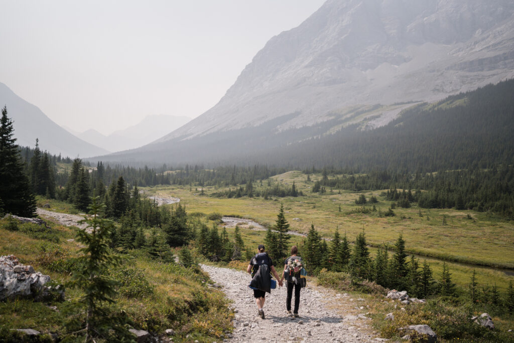 couple walks down a trail in kananaskis after their backcountry camping elopement