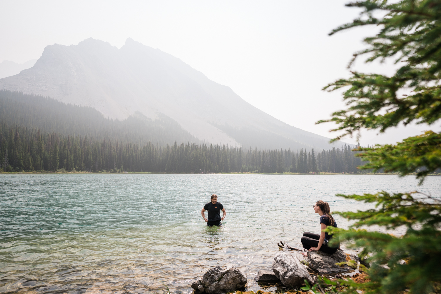 Couple swims in Elbow Lake after a camping elopement in Kananaskis. 